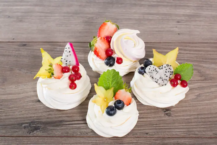 Mini bezy Pavlova z kremem, truskawkami, borówkami, czerwoną porzeczką i karambolą